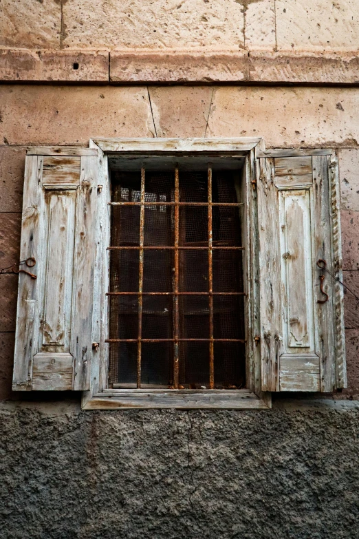 a window with wooden shutters and bars inside