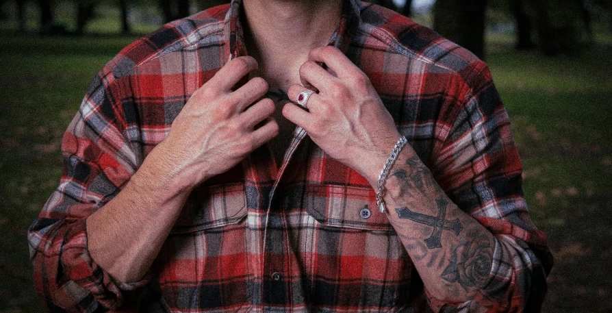 man in a plaid shirt showing off his small tattoo