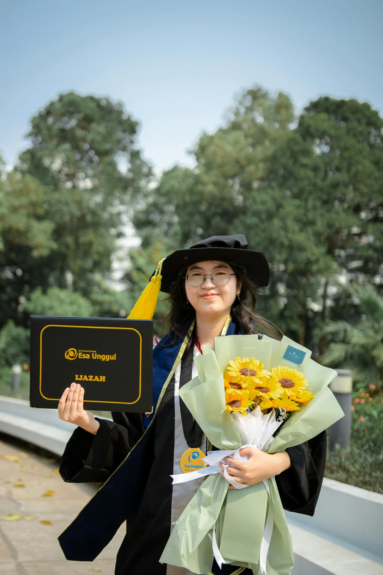 woman holding flowers and wearing cap and gown