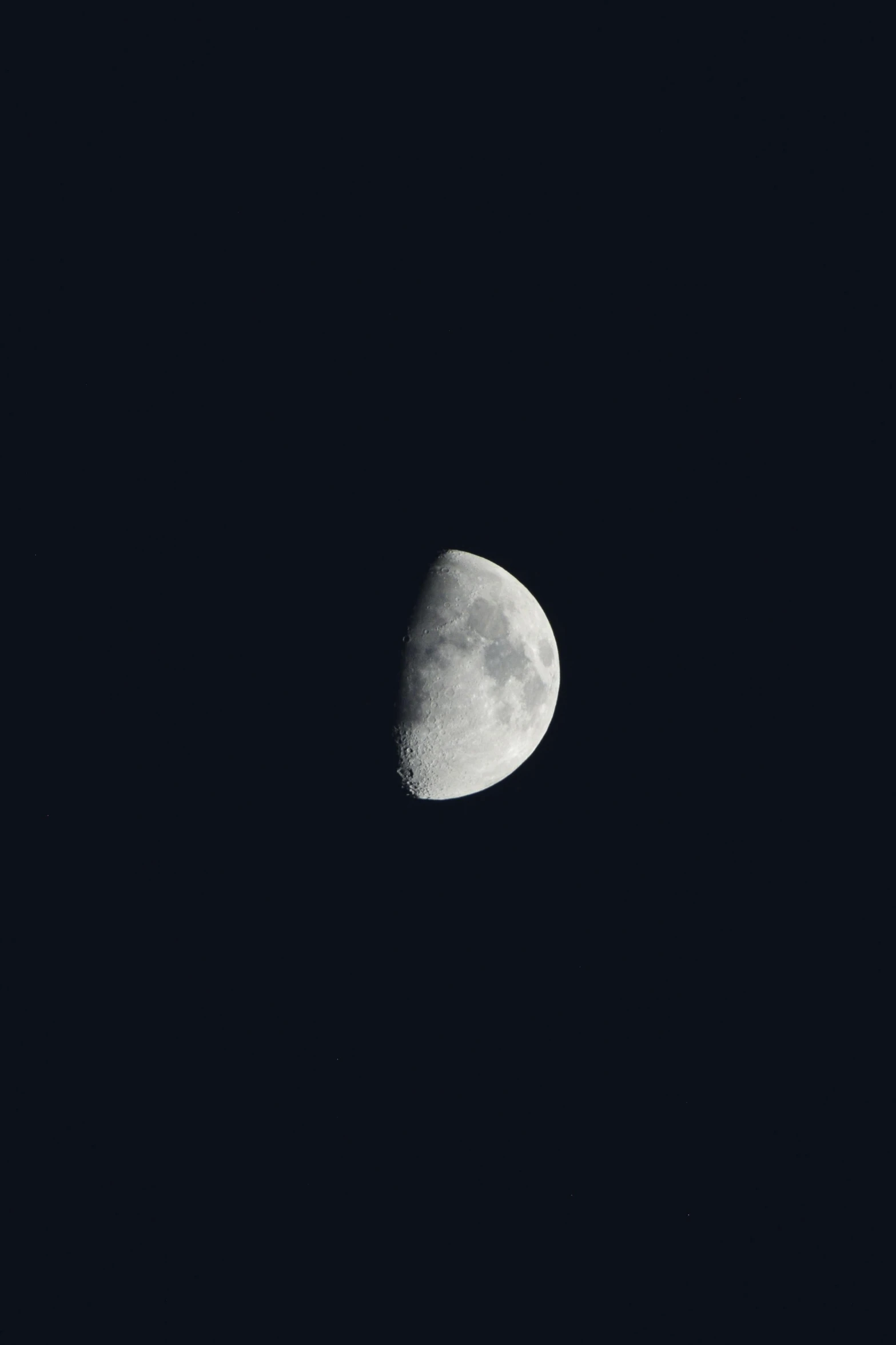 a half moon in the night sky is seen with dark clouds