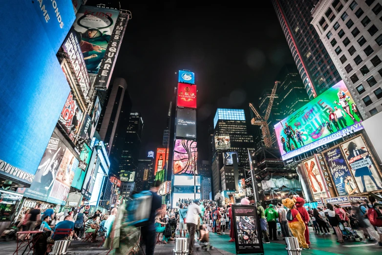 the night time view of times square with people crossing in the city