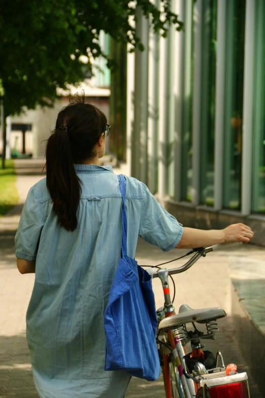 a woman carrying her bike down the street