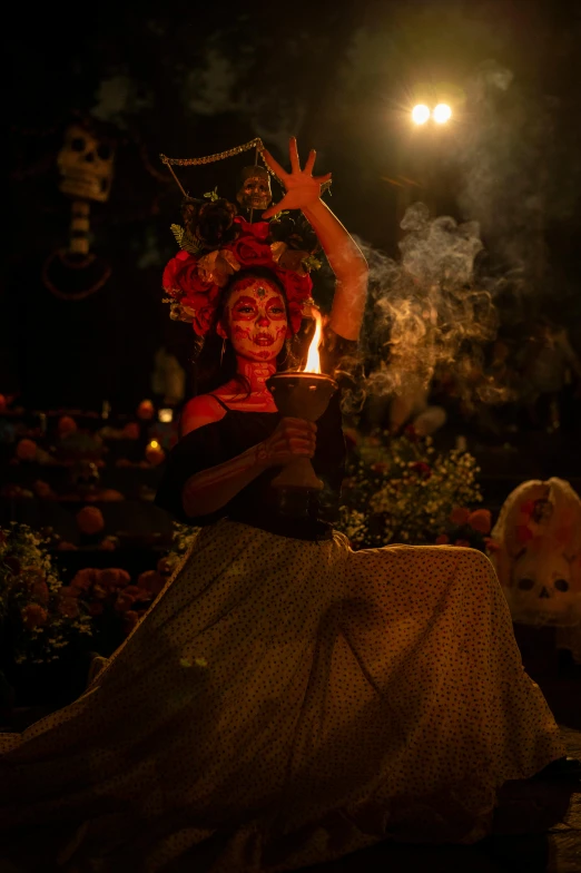 a woman sitting down wearing a costume and holding a lit candle