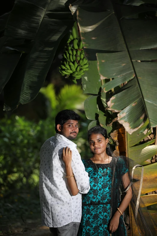 a man and a woman are posing by banana trees