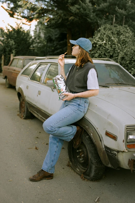 a woman sitting on the back of an old white car