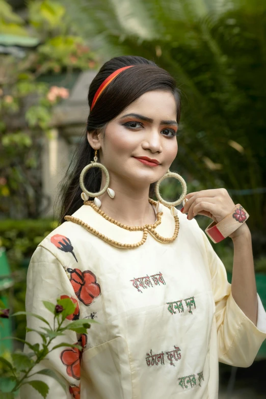 a girl wearing big hoop earrings and a flowered dress poses for a picture