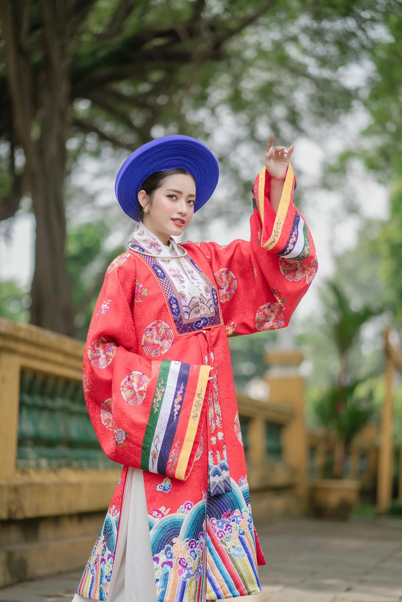 a young woman in a colorful traditional dress and blue hat poses for a po