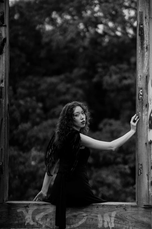 black and white pograph of woman sitting on door