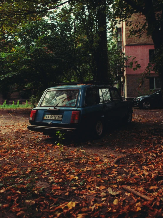 a car in a lot near some trees and leaves