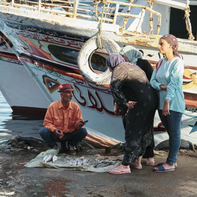 two people next to a fishing vessel with a small elephant on the dock