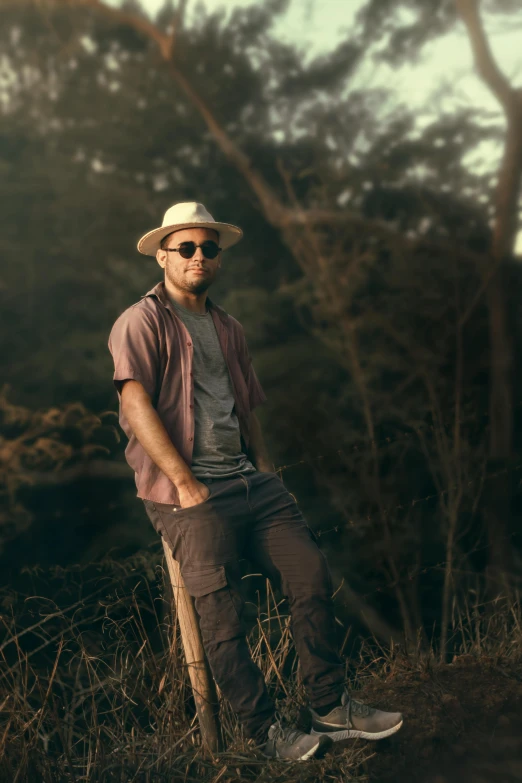 a man with a hat, sunglasses and standing in a field