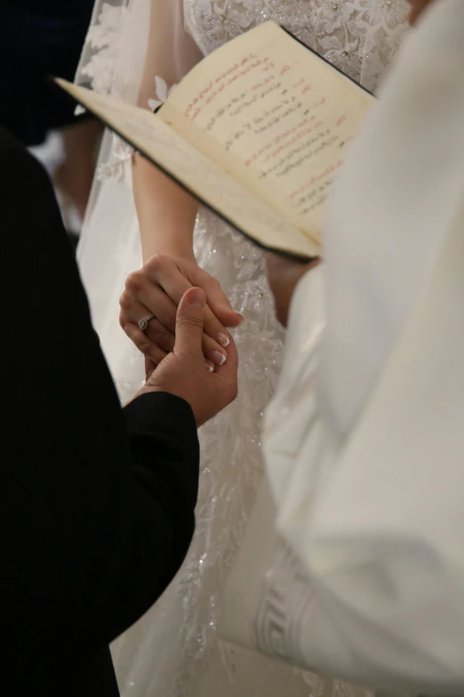 a woman holding the hand of a man with a book in her hands