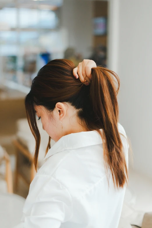 the back of a woman's head with her hair pinned in top knot, sitting on a counter top