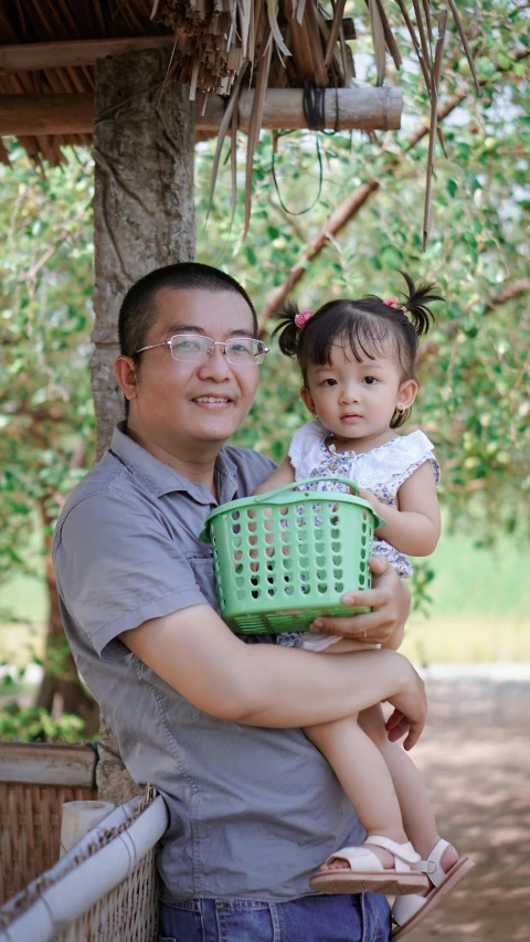 the father and daughter are outside holding a laundry basket