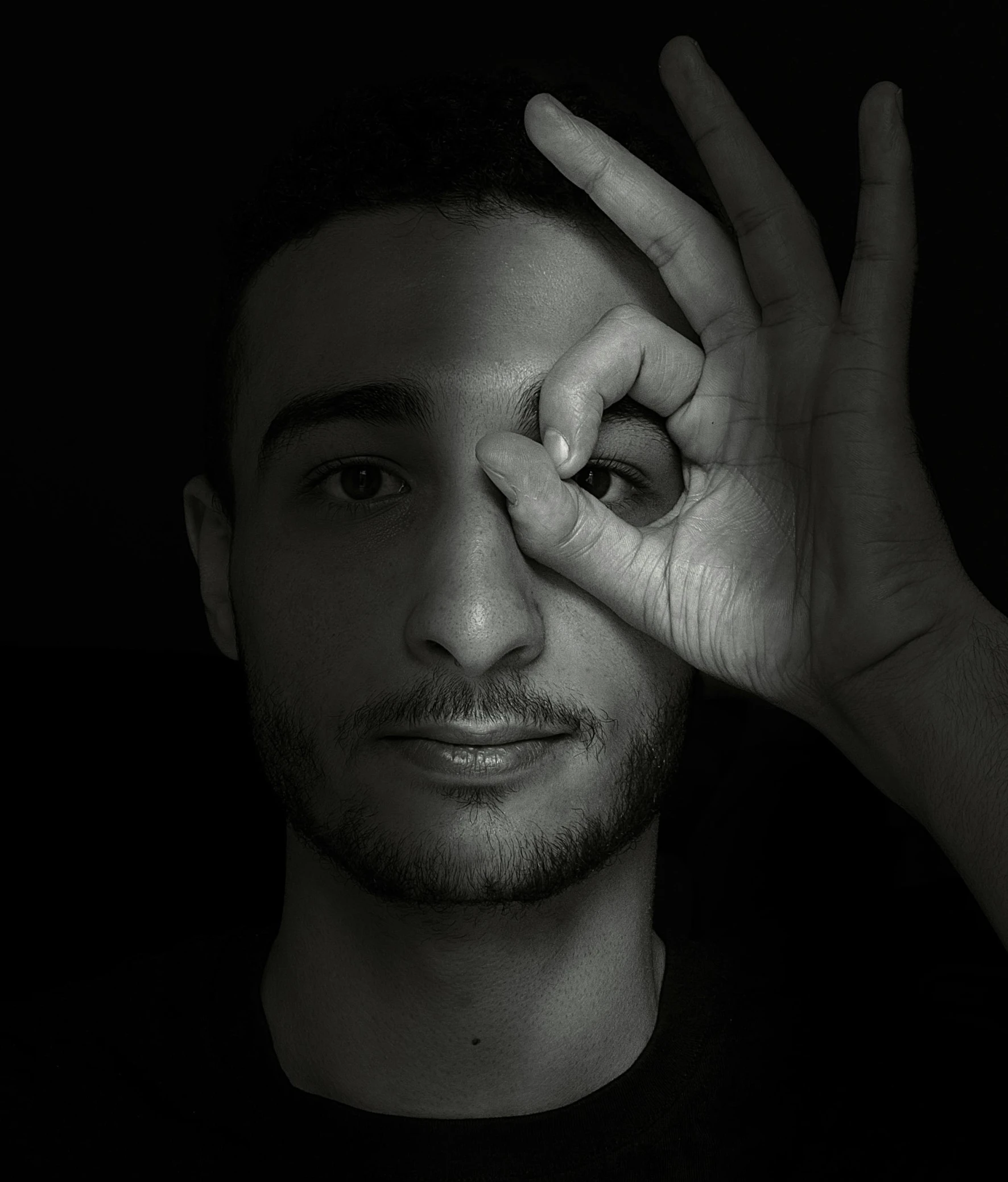 a black and white picture of a young man with his hand over the eye