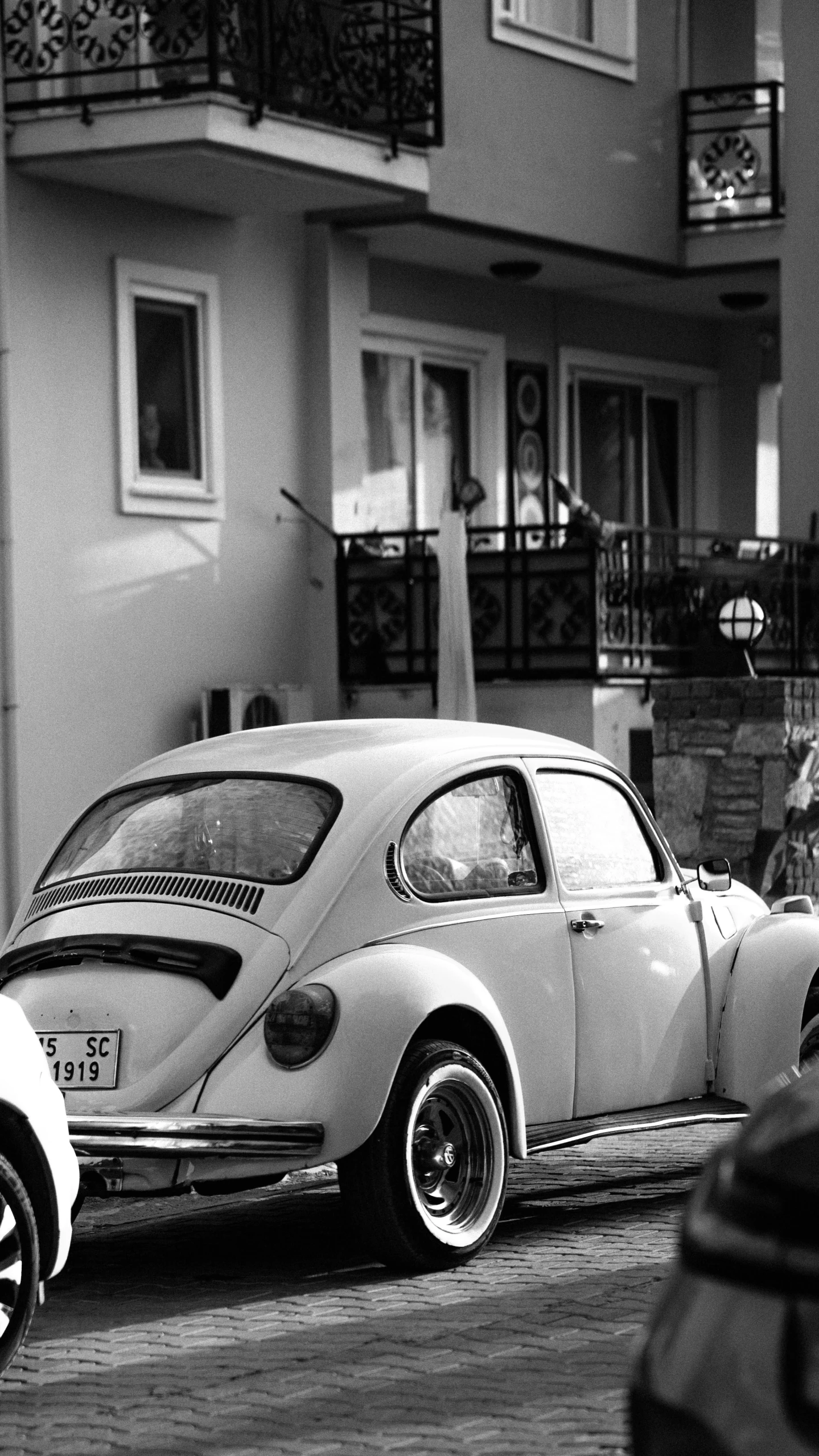 an old fashioned vw bug parked next to a tall building