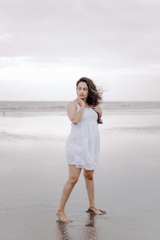 a woman in white on the beach with a long flowing hair