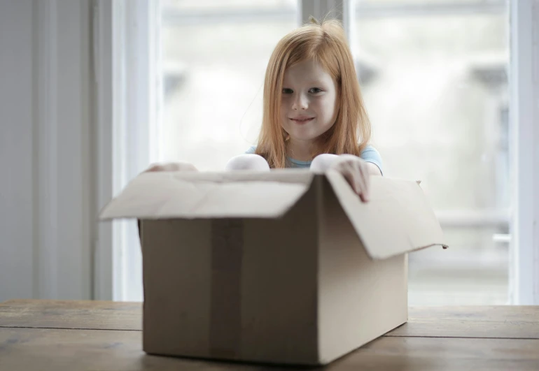 a girl looks out of a cardboard box