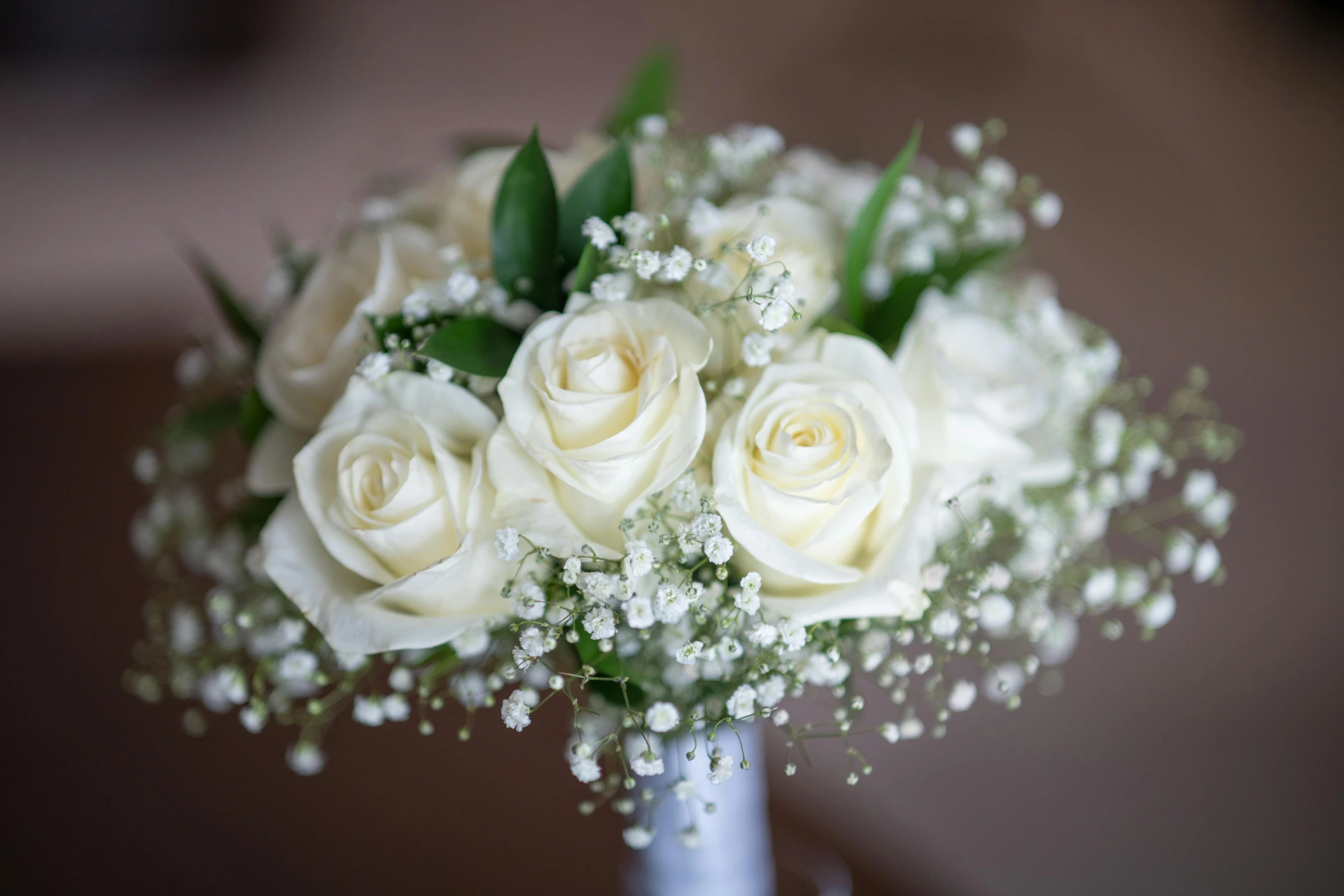 a vase filled with white roses and baby's breath