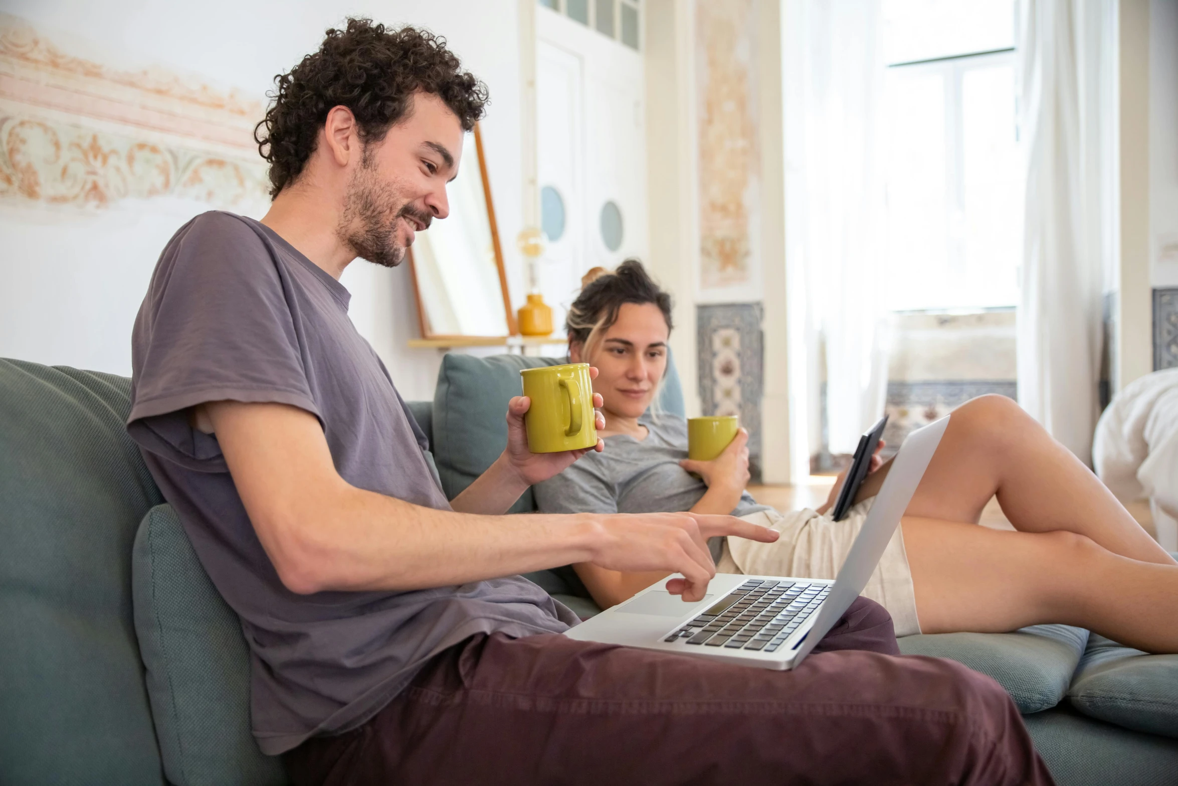 man and woman sitting on a couch with their legs crossed while looking at a laptop computer