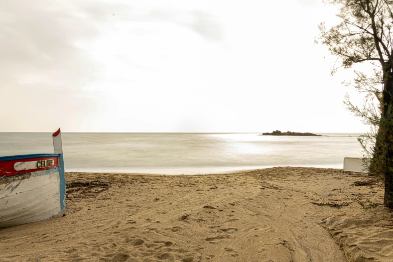 a canoe resting on the beach next to some water