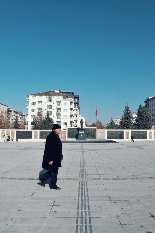 a man standing on the pavement in front of a white building