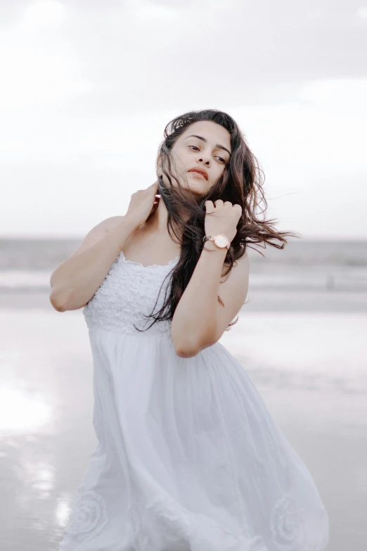 a beautiful woman posing in white dress at the beach