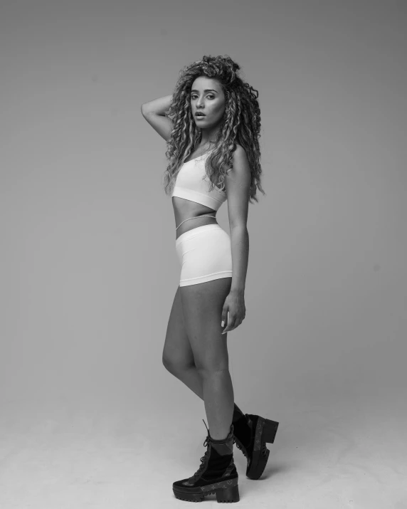 a woman with long curly hair standing in shorts and combat boots