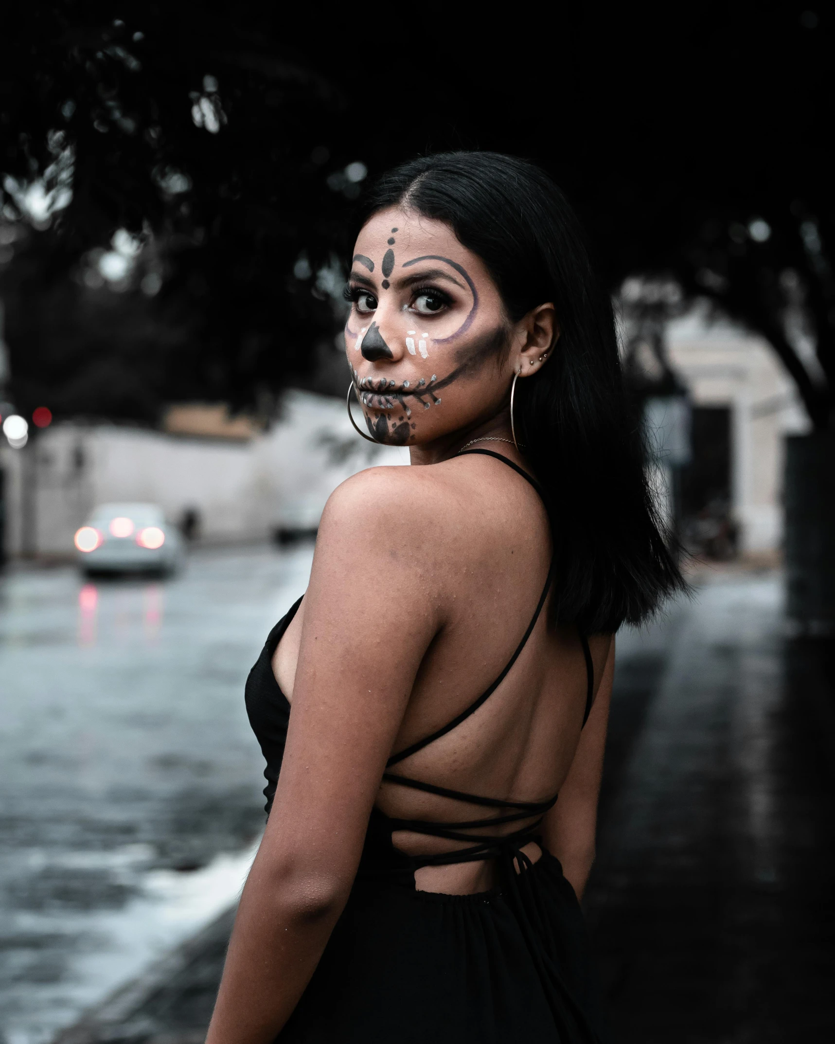 a woman with face painted in white, is looking at the camera