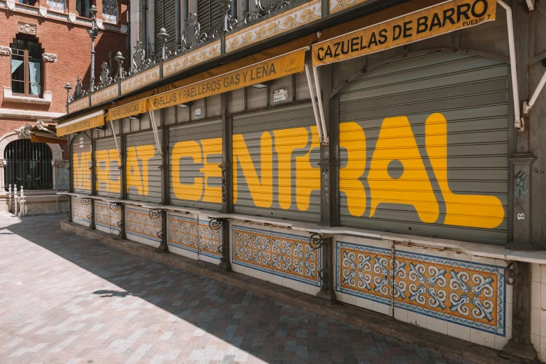 a yellow and gray store front with letters painted on the side