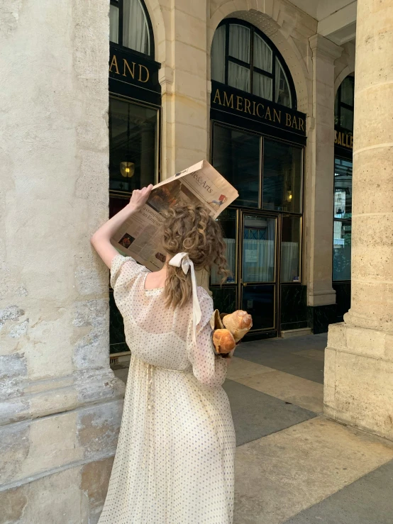 the woman is standing in front of a building and reading a newspaper