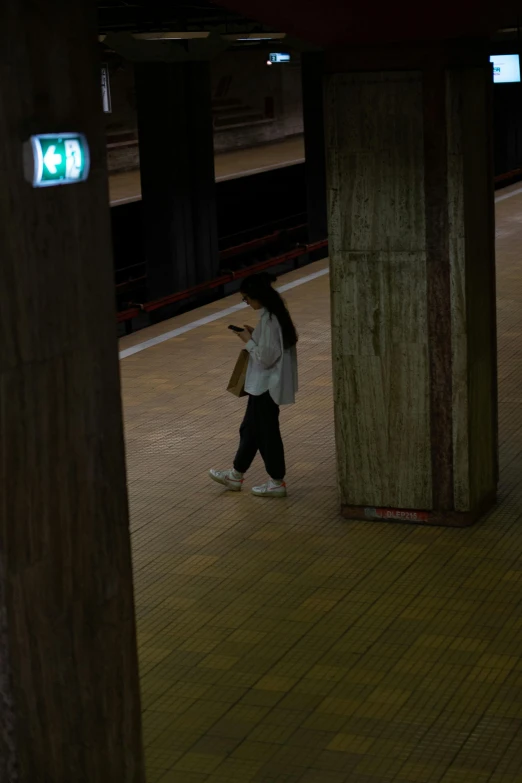 a person walking down the platform next to train tracks