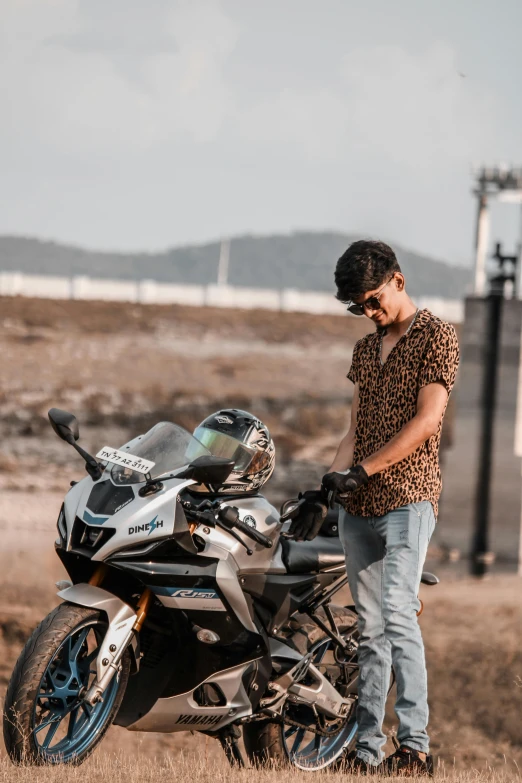 a man with a helmet on his head stands next to a motorcycle