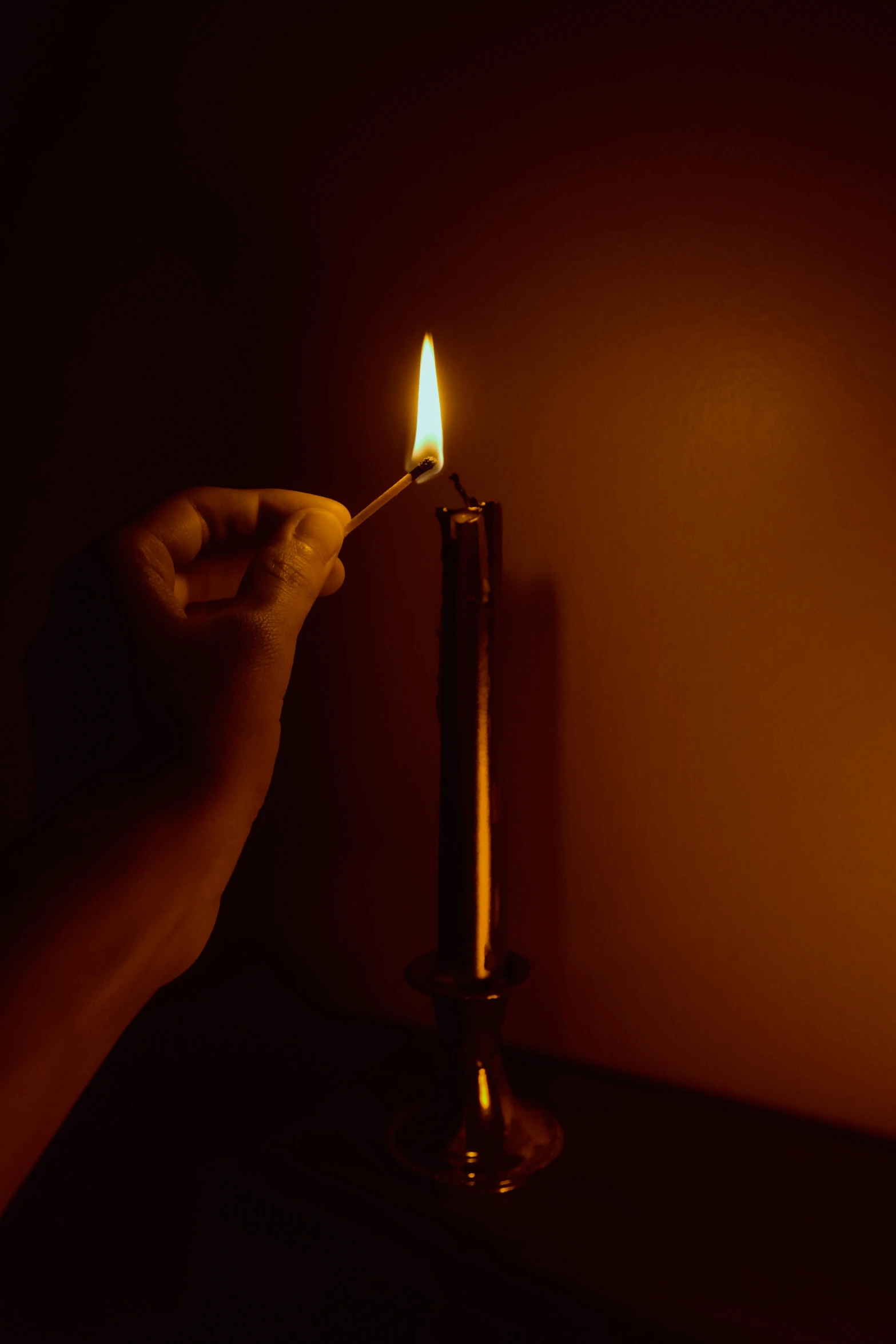 someone lighting soing with a candle in a dark room