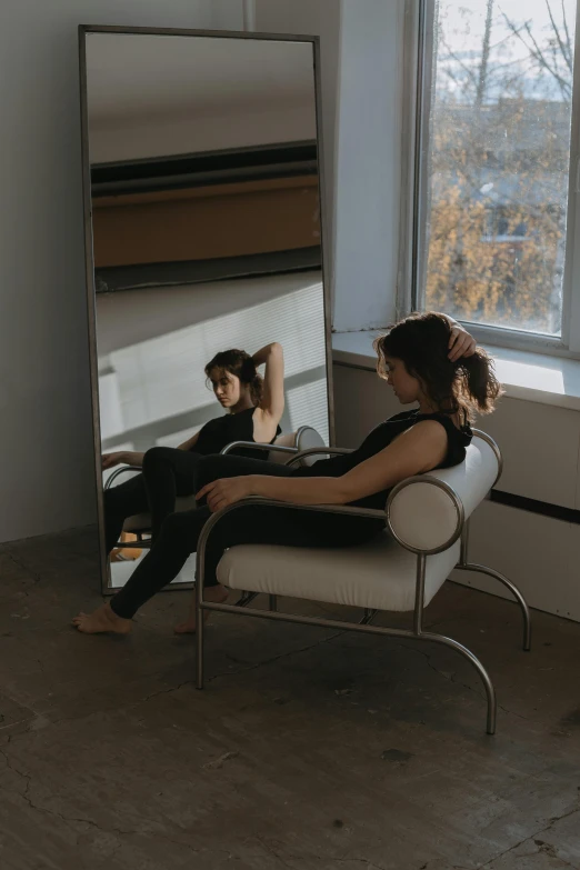 a woman sitting on a chair in front of a large mirror