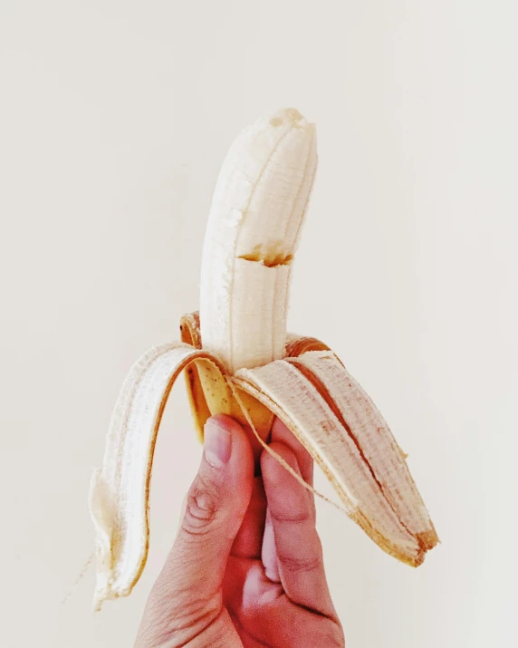 person holding a peeled banana in their hand