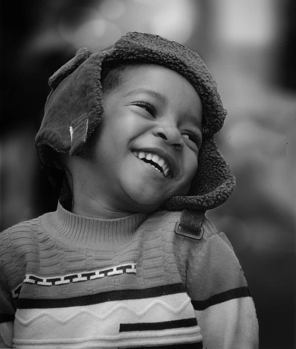 a boy is smiling while wearing a sweater and hat