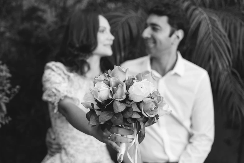 the man is holding his bouquet while his lady stands near him