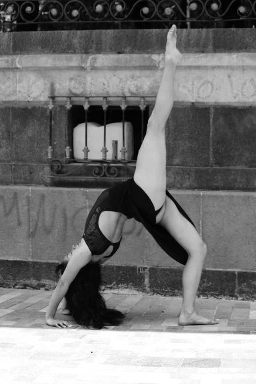 a woman practices a yoga pose on the pavement