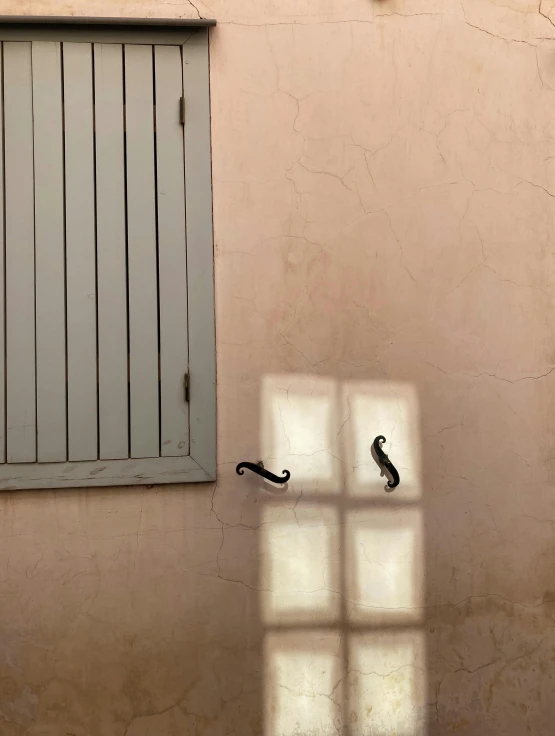 a shadow on a wall, with a window and a shutter