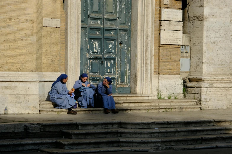 three girls are sitting on the steps and talking