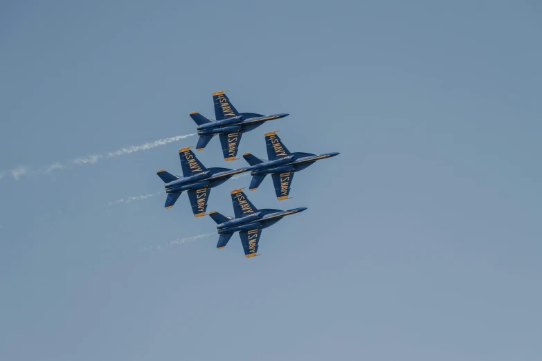 four blue angels jets flying in formation against a clear sky