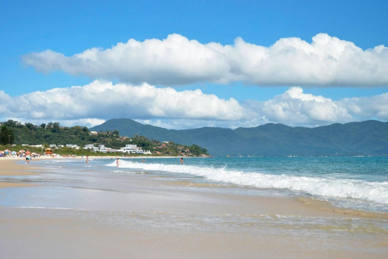 people walk the sandy shore next to the ocean