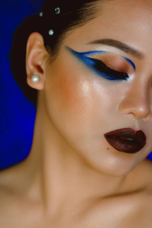 a woman with dark blue eye makeup looks to her left