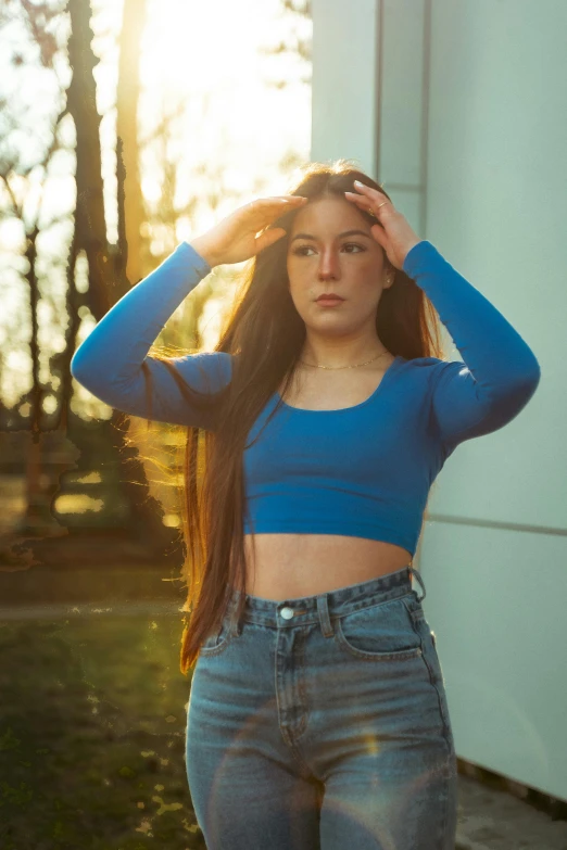 young woman in jeans poses at sunset