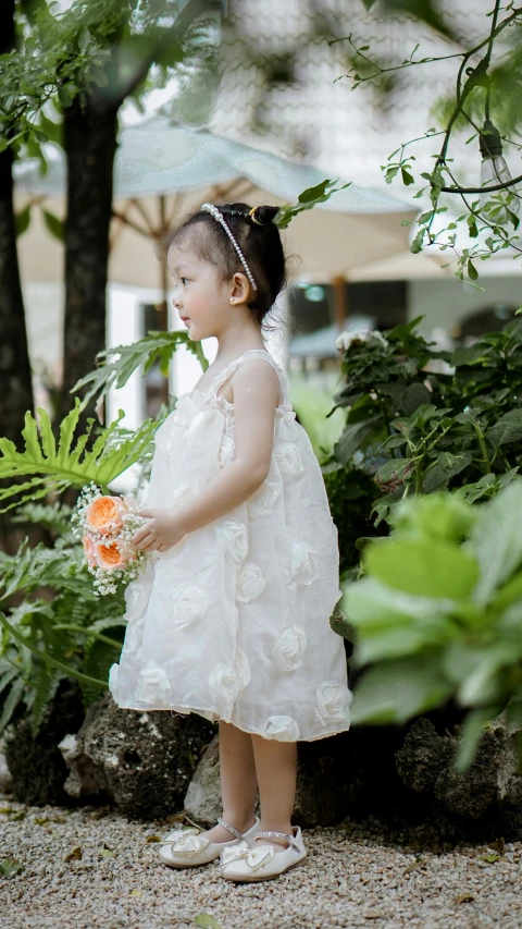 a little girl in a short dress holds an umbrella over her head