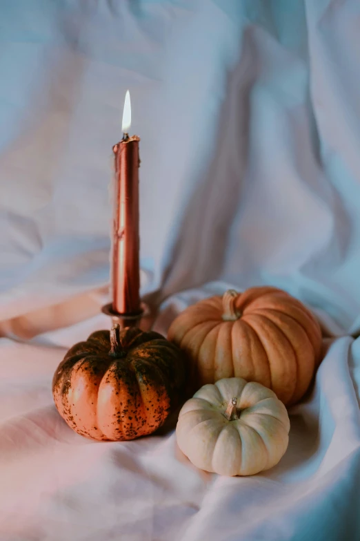 a candle on top of a table with pumpkins on the side