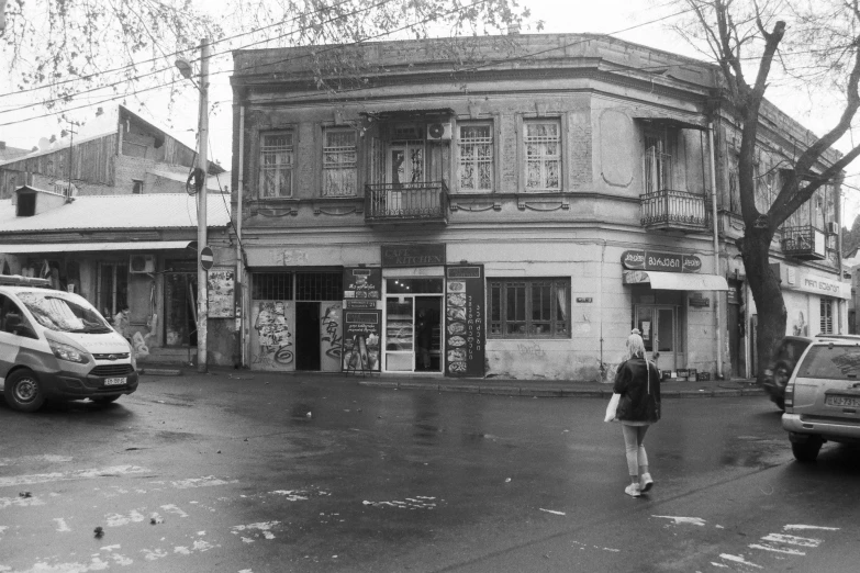 an old black and white pograph shows a person crossing the street