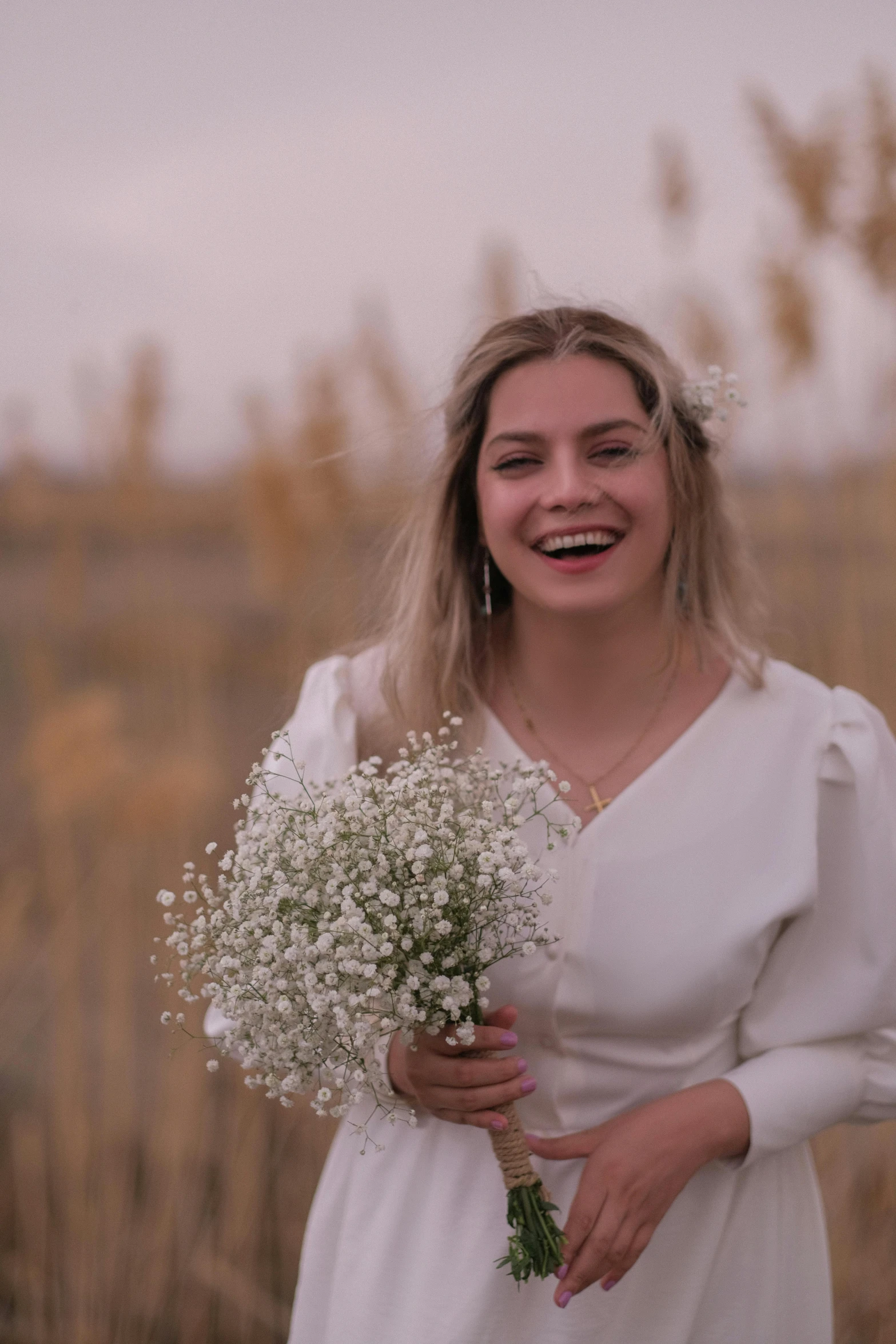 the young woman is smiling holding the white flowers