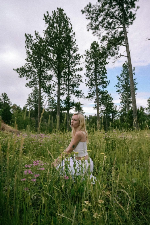 a girl is sitting in a field of tall grass